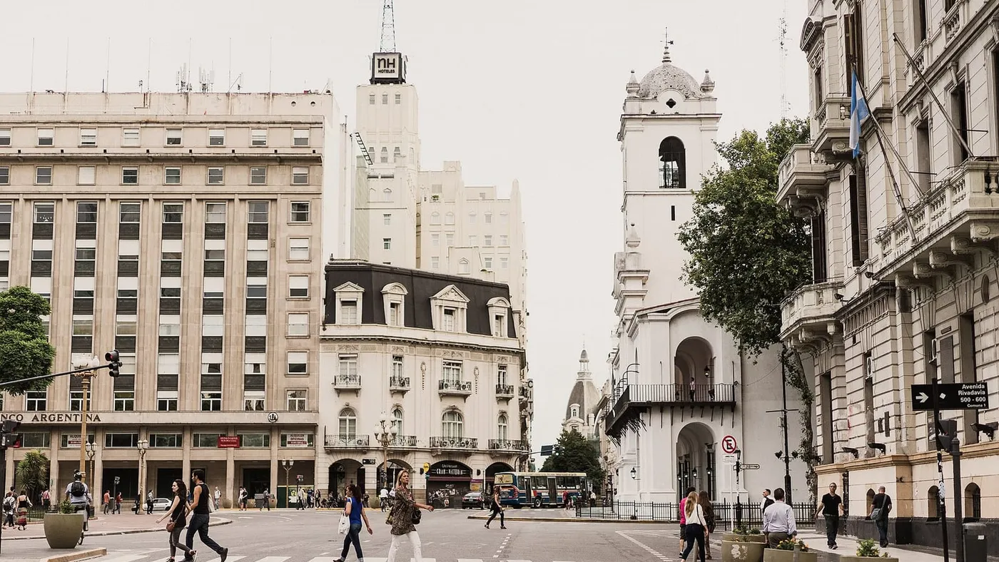 Peatones cruzan una calle del centro histórico de Buenos Aires, rodeada de edificios antiguos y el Cabildo