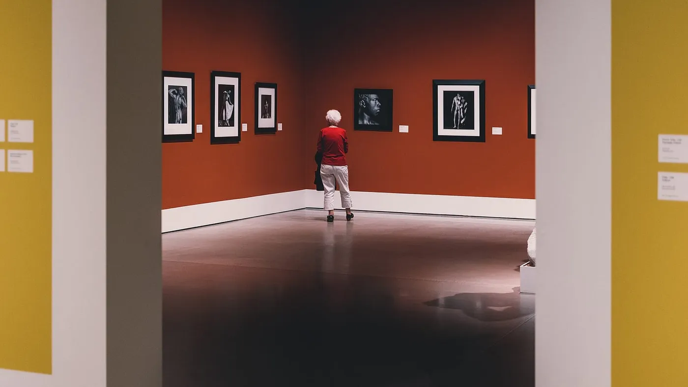Una mujer mayor observa en soledad las fotografías colgadas en la sala de un museo