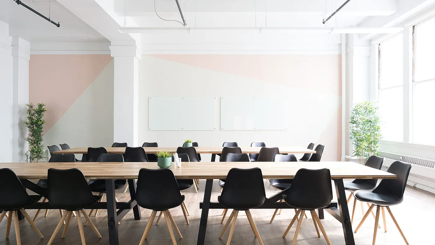 Una sala de reuniones luminosa con una mesa larga de madera y sillas negras