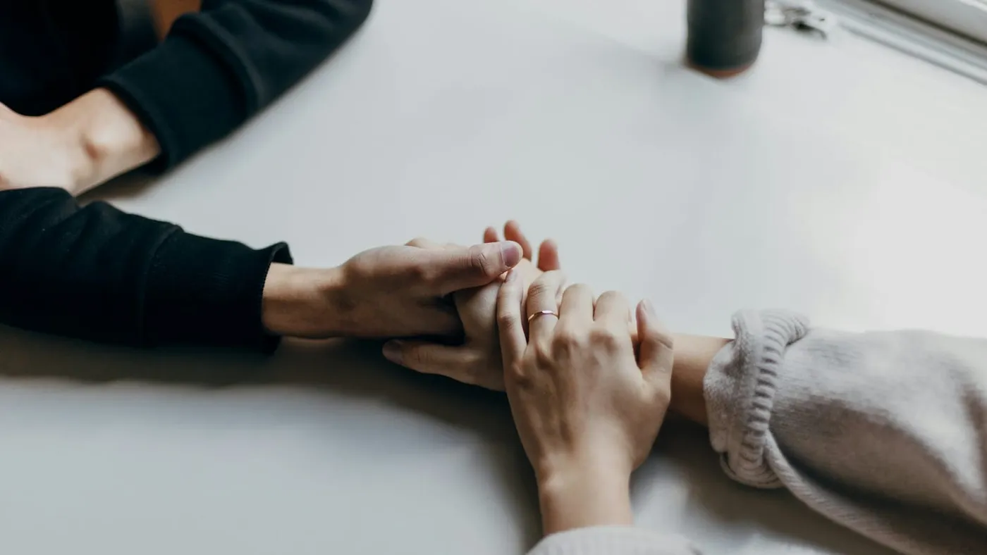 Dos personas se toman de las manos sobre una mesa