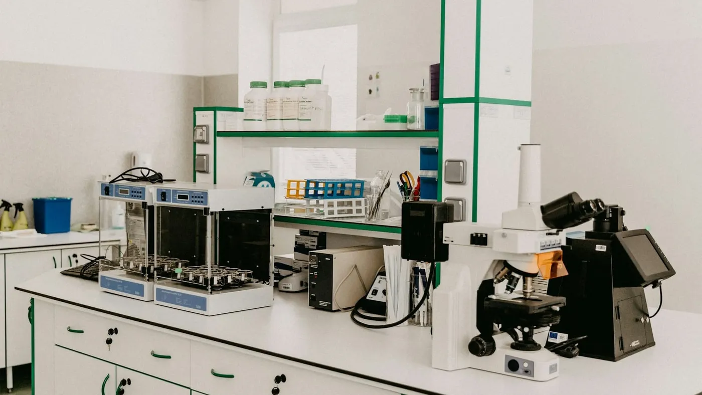 Una mesada de laboratorio con un microscopio y equipos de análisis en una sala luminosa