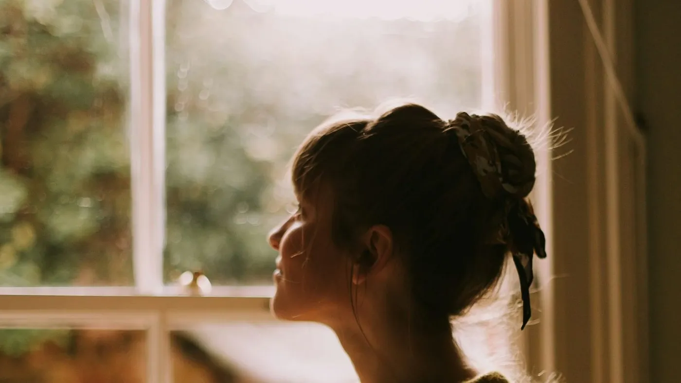 Mujer junto a una ventana sostiene una taza de té